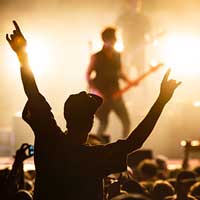 Live music fan rocking out at a concert with guitar player on the stage